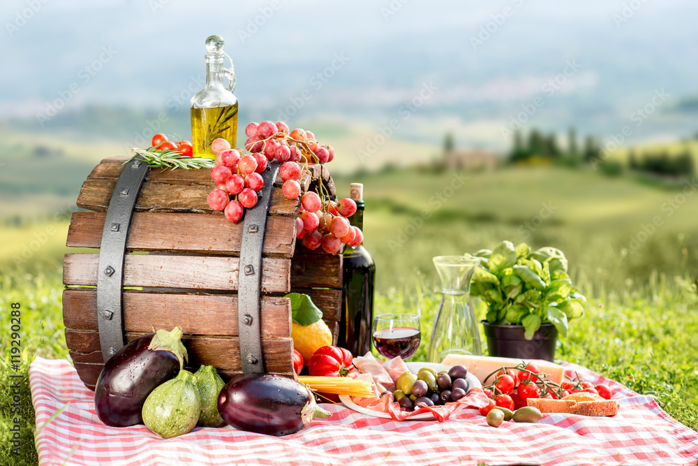 Fototapeta premium Lots of tasty italian food on the napkin and wooden barrel outdoors on the tuscany landscape background