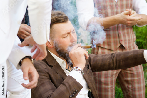 Stylish handsome guy enjoying cigarette with friends