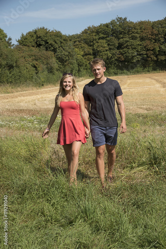 Couple in Hampshire countryside England UK - A young couple walking on farmland in the English countryside