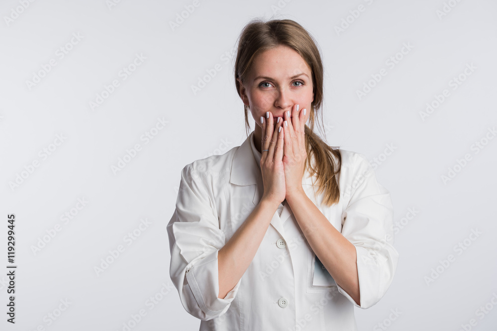 Young female doctor or nurse is shocked with hands on her mouth Young female doctor or nurse is shocked with hands on her mouth