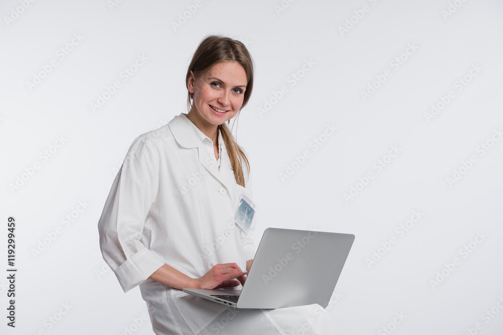 Smiling female doctor working on her laptop against a white background Smiling female doctor working on her laptop against a white background