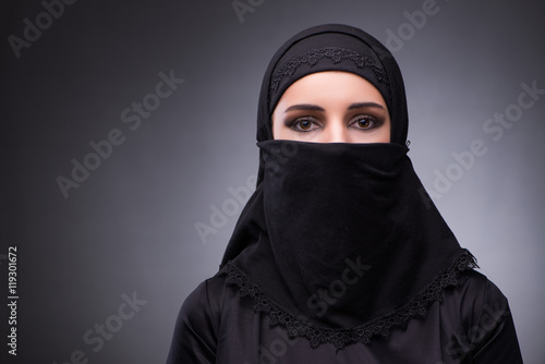Muslim woman in black dress against dark background photo