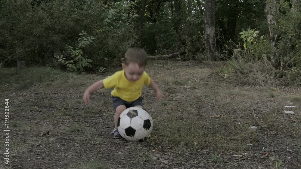 young boy running with soccer ball on the road