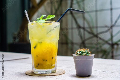 Yellow Sparkling Drink : Passion fruit-Mango Soda to quench your thirst on the wooden table with small Cactus decoration 