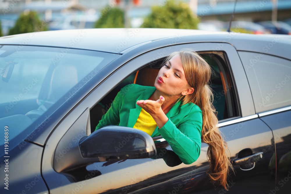 Girl behind wheel of car sends air kiss