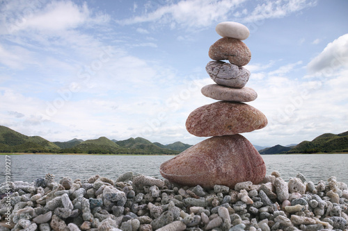 Balance stone on pile rock with river background.