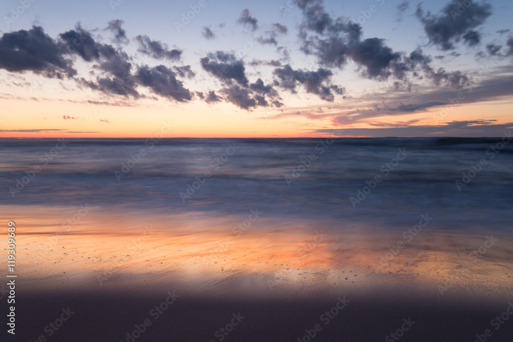 Fototapeta premium Beautiful sunset at the beach after a summers day, reflections in the water