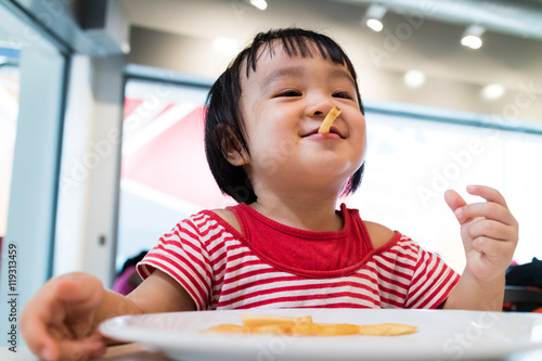 Asian Chinese little girl eating french fries