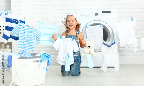 child fun happy little girl  to wash clothes and laughs in laund photo