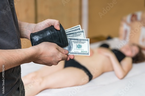 Quadro su tela Man is paying with dollars a young prostitution for her work.