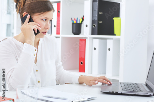 Business woman working on her laptop and talking on the phone.