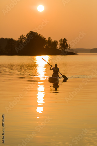 Paddle-boarding on lake during sunset © petejau