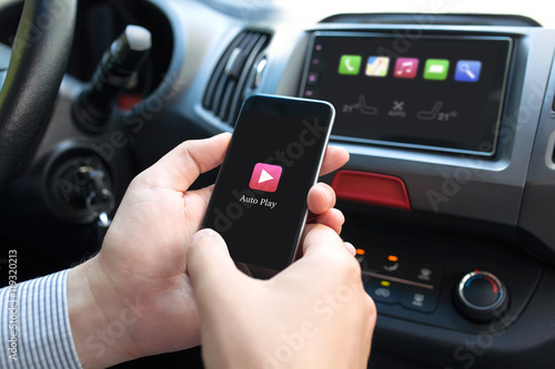 man hand in car holding phone with Auto Play multimedia