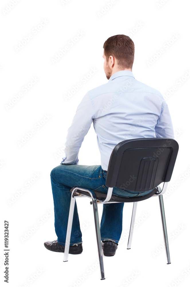 back view of business man sitting on chair. Bearded businessman in white shirt sits on a chair and looking forward.