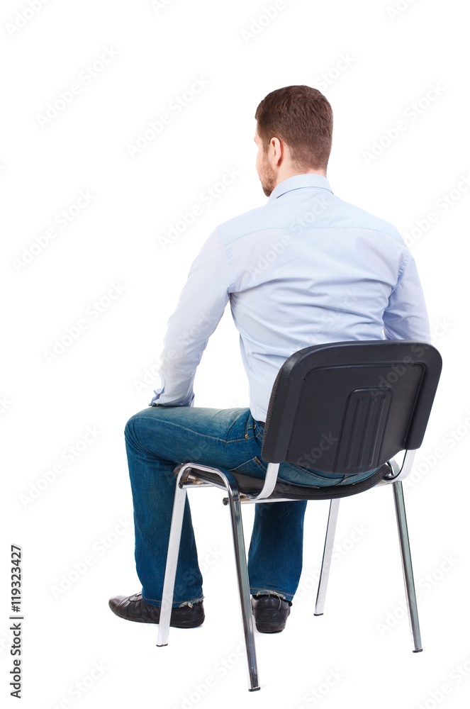 back view of business man sitting on chair. Bearded businessman in white shirt sits on a chair and looking forward. back view of business man sitting on chair. Bearded businessman in white shirt sits on a chair and looking forward.