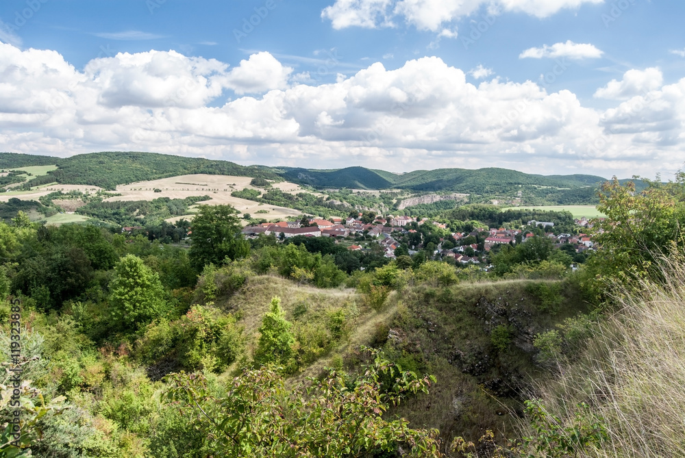 summer countryside with village, forests, meadows, fields, small hills and blue sky with clouds in Central Bohemia 