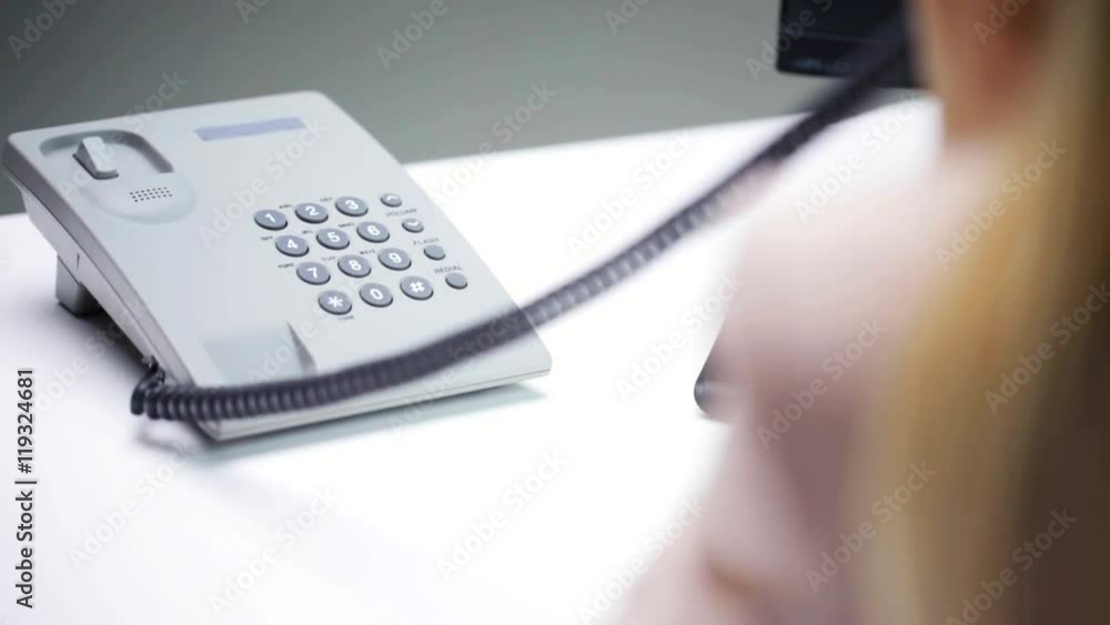 woman hand dialing number on telephone at office woman hand dialing number on telephone at office
