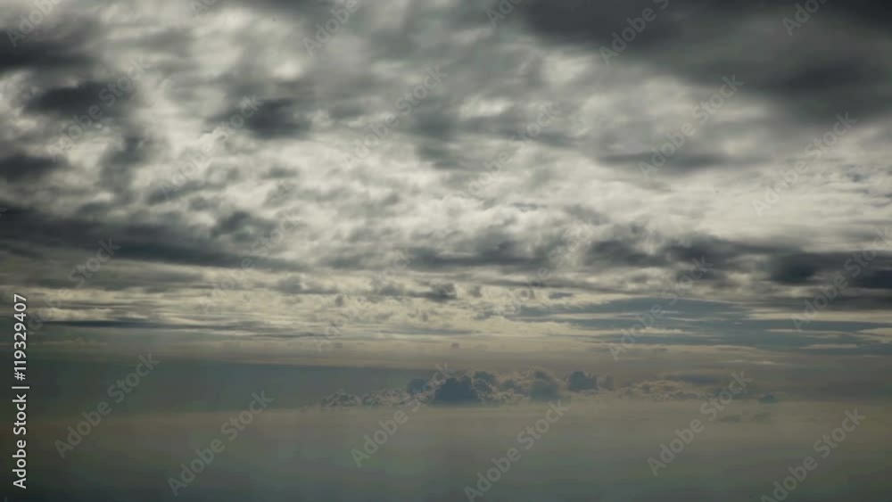 The sky looks very grey and there are many clouds seen. A plane is flying from one destination to another. Wide-angle shot.
