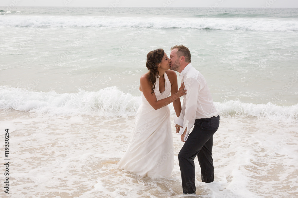 Newlyweds sharing a romantic moment at the beach kissing Newlyweds sharing a romantic moment at the beach kissing
