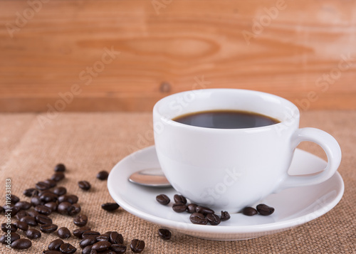 Coffee cup and coffee beans on wood table in coffee shop