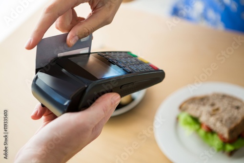 Hand holding a credit card next to the tablet