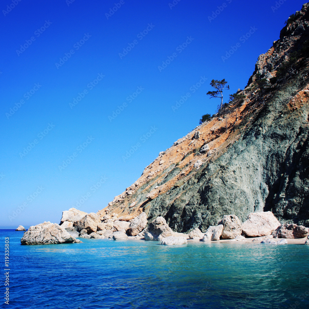 Rocky shore. Southern coast of Turkey. Calm blue sea and clear sky. Small beach on the island near Adrasan. View of Mediterranean Sea. Spring sunny day in Antalya province, Turkey.