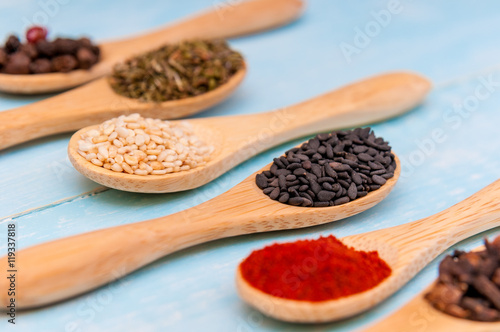 Various spices on wooden spoons. Food ingredients. Blue rustic wood table