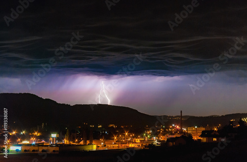 Thunder storm electric lightning strike dark night overcast sky city town landscape 