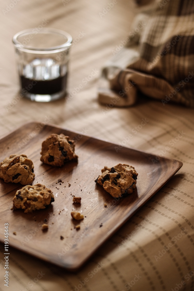 Chocolate chip cookies with the coffee on a wooden plate at the bedroom.
Chocolate chip cookies with the coffee on a wooden plate at the bedroom.