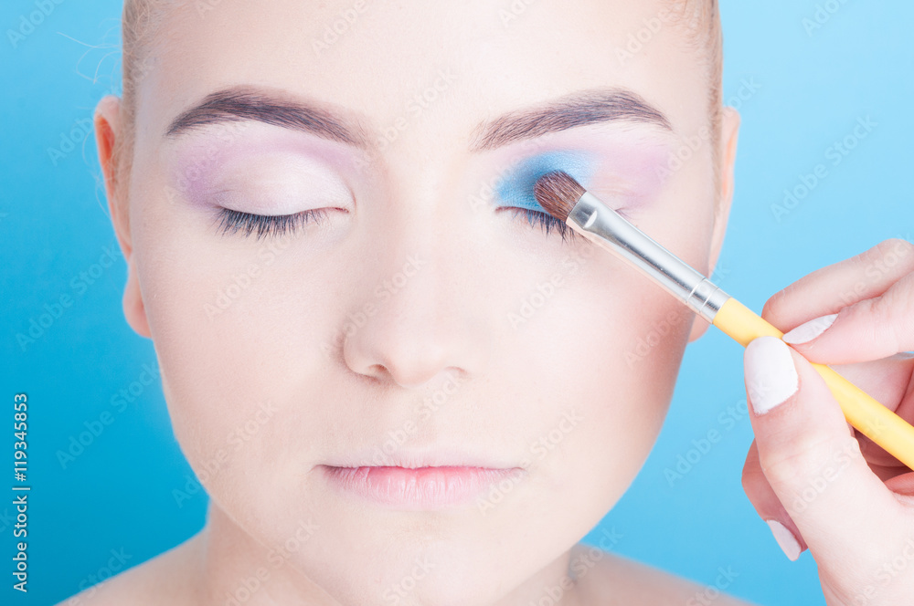 Close-up of applying blue eyeshadow on young woman