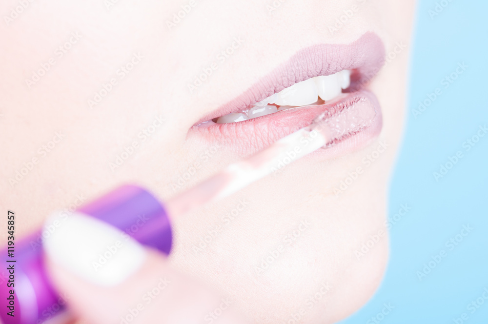 Naklejka premium Close-up of lips with brush applying glossy lipgloss