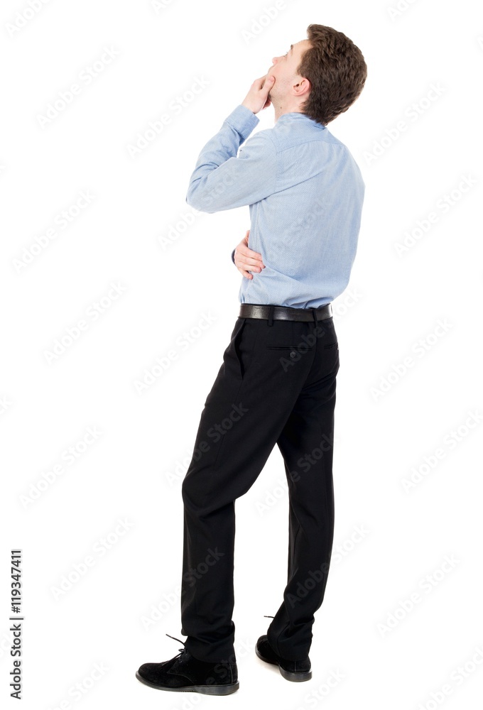 back view of standing business man. curly-haired businessman in light shirt looking up thoughtfully. back view of standing business man. curly-haired businessman in light shirt looking up thoughtfully.