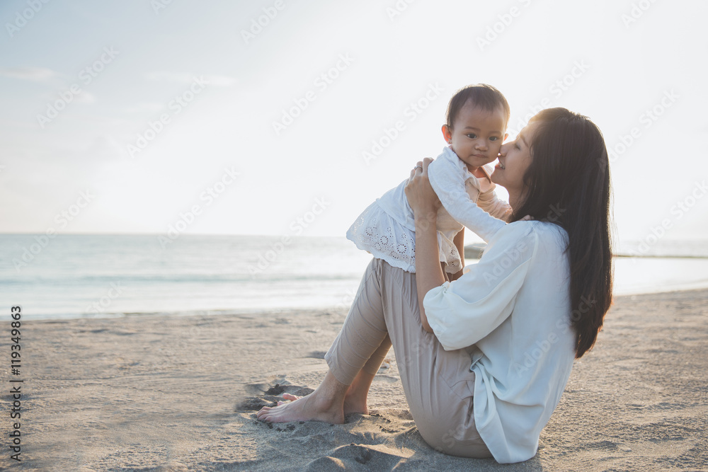 Portrait of mother and baby in the beach at sunset