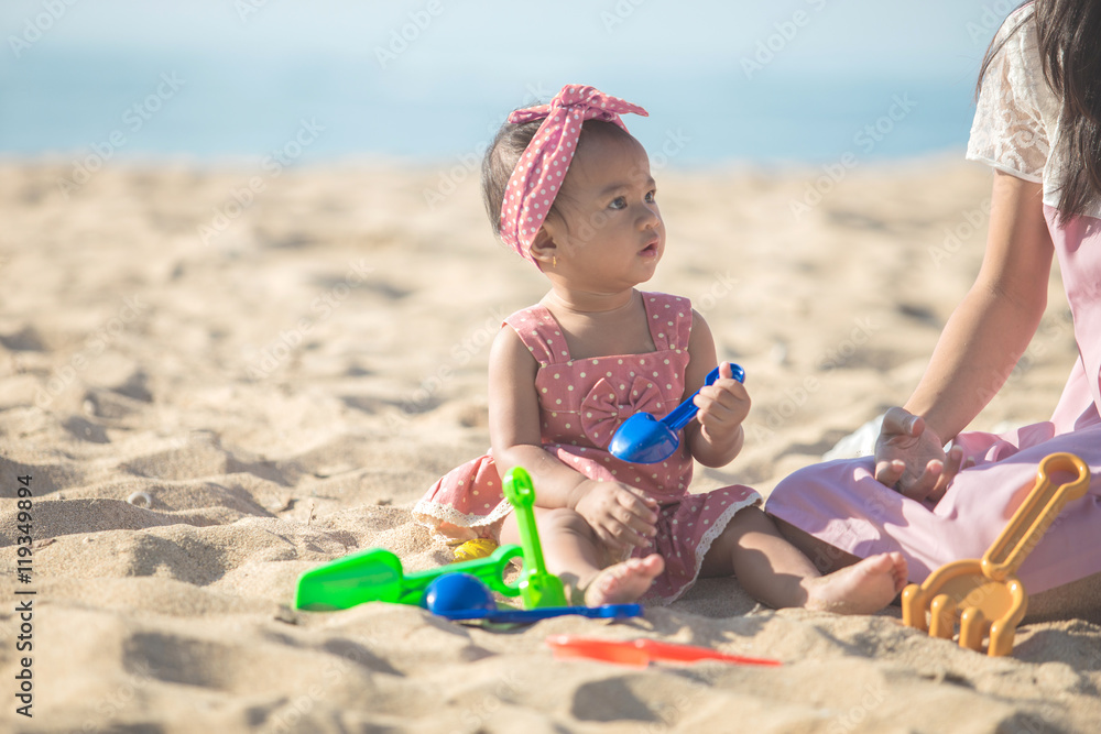 baby girl with mother at the beach play with toys on the sand baby girl with mother at the beach play with toys on the sand
