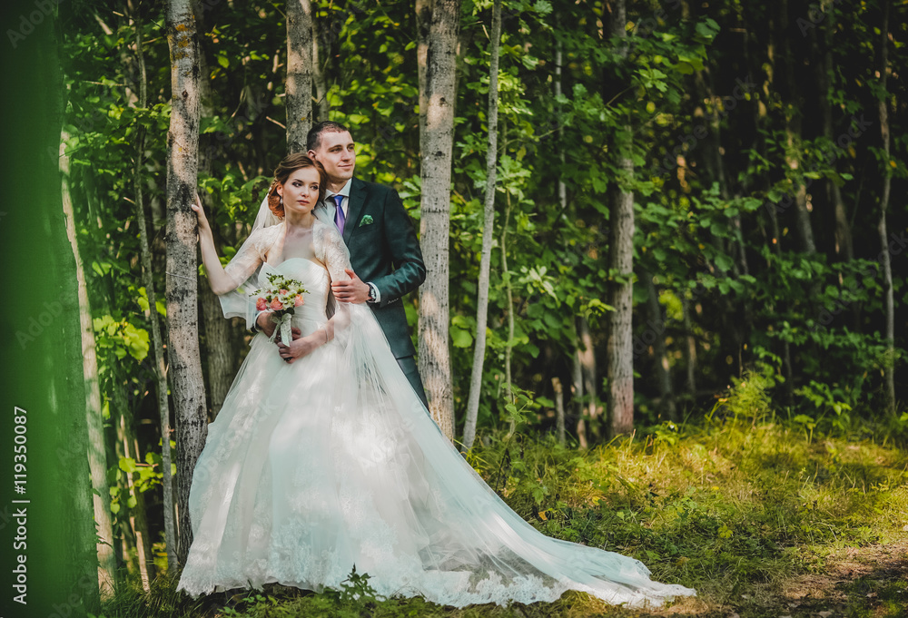 Fototapeta premium bride and groom kissing and embracing in the forest