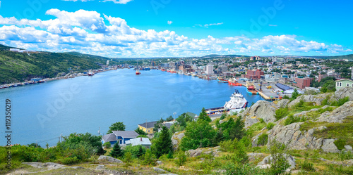 Panoramic views with bight blue summer day sky with puffy clouds over the harbour and city of St. John's Newfoundland, Canada.