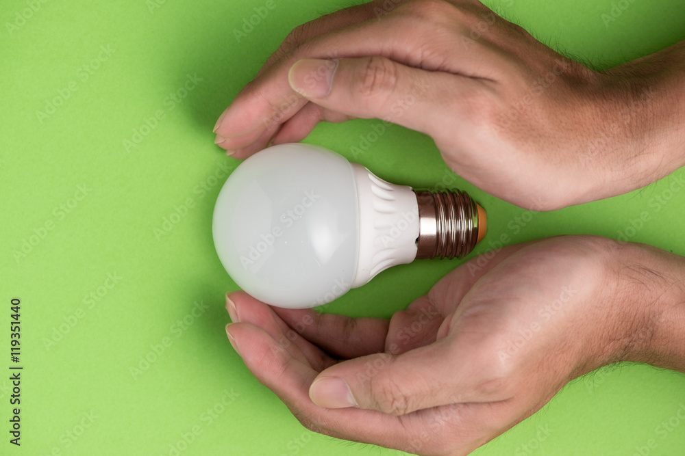 Hands guarding energy saving eco lamp close up Hands guarding energy saving eco lamp close up