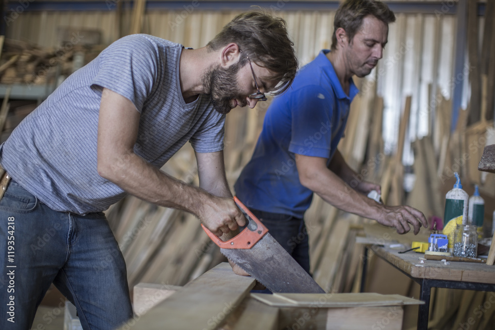 Carpenter working with crosscut saw in workshop Carpenter working with crosscut saw in workshop