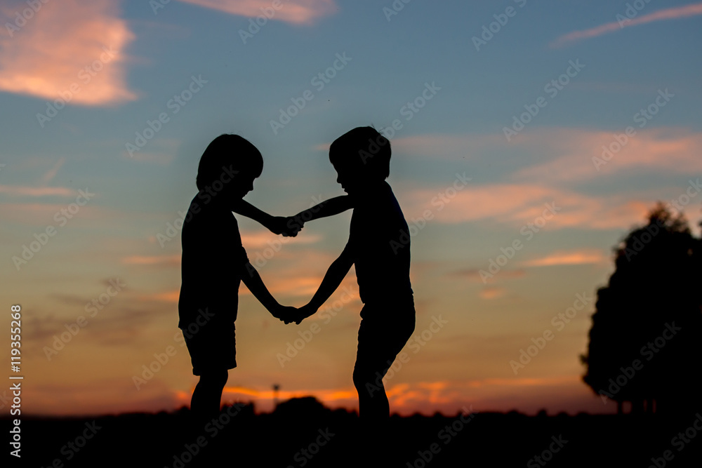Silhouette of two children, boy brothers, making heart shape wit