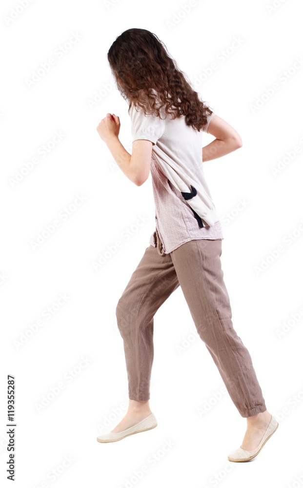 Obraz widok z boku biegnącej kobiety. piękna dziewczyna w ruchu. Długowłosa dziewczyna z kręconymi włosami biegnie obok kamery.