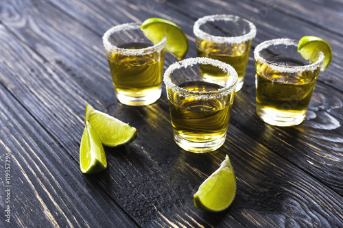 Gold tequila with lime and salt on dark table