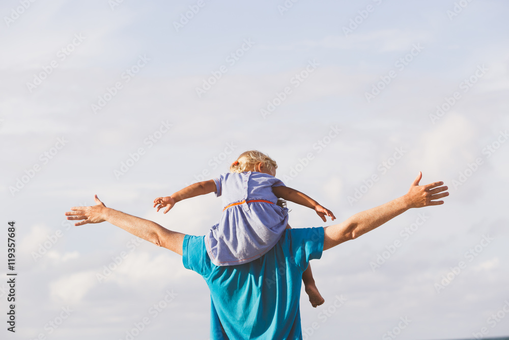 father and daughter on shoulders play at sky