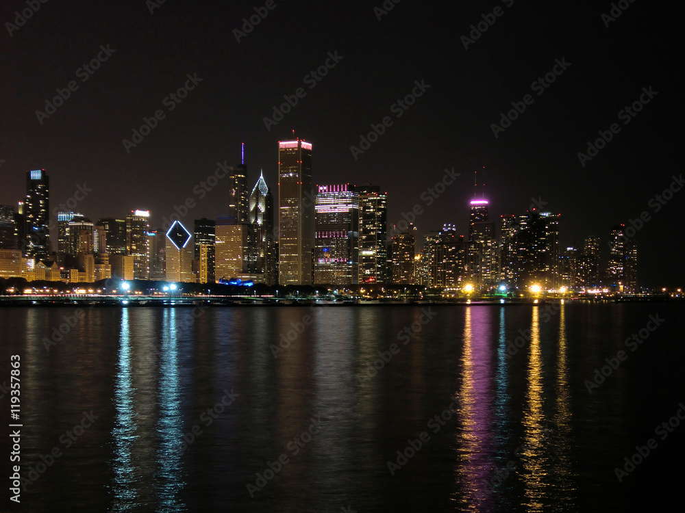 Chicago skyline at night across water with reflections