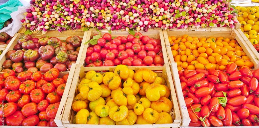 Crate of colorful tomatoes and radishes at a French farmers market