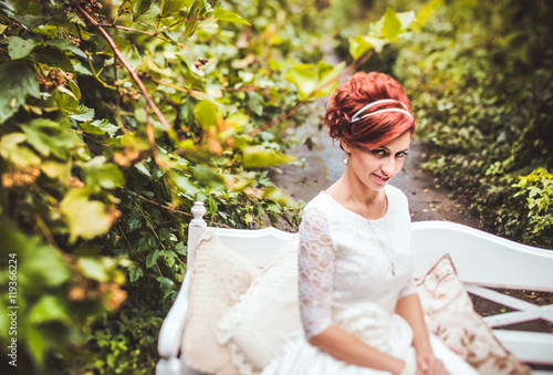 Portrait of beautiful red hair woman in white dress in the park 