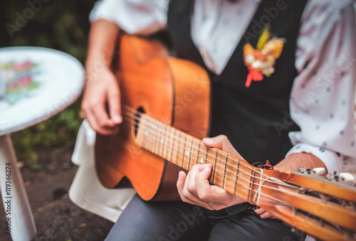 close up finger of guitarist while playing guitar in the outdoor garden