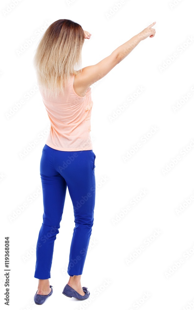Back view of pointing woman. Isolated over white background. Blonde in blue pants I saw something in the distance. Back view of pointing woman. Isolated over white background. Blonde in blue pants I saw something in the distance.