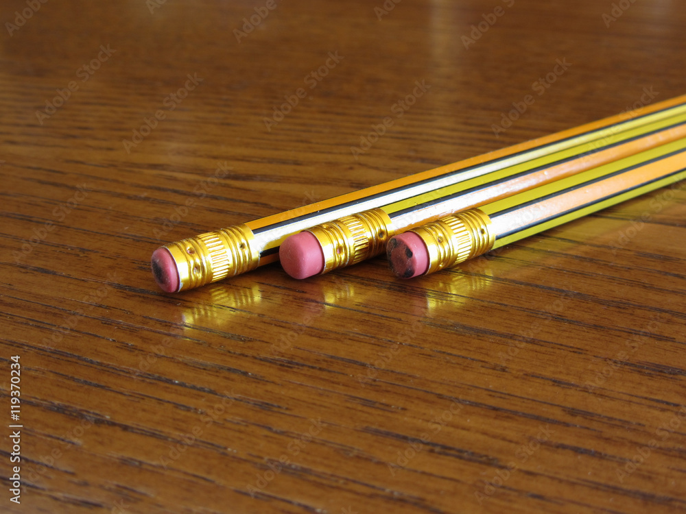 Closeup of used pencil erasers on wooden table