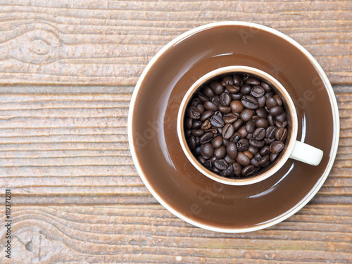 one cup of coffee beans and plate on the wood background