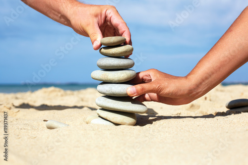 Man and woman together to build a tower made of stones.